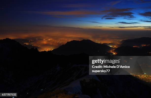 the lights of the po plaine below a fog layer from the the top of a mountain - pianura padana foto e immagini stock