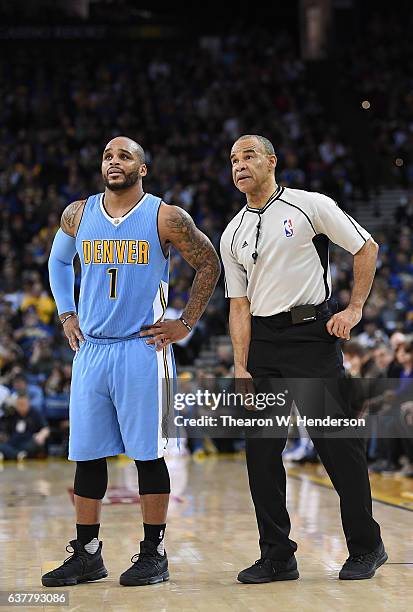 Referee Dan Crawford talks with Jameer Nelson of the Denver Nuggets during a break in the action of an NBA basketball game against the Golden State...