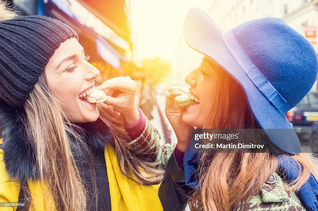 Mujeres felices comiendo macarrones parisienses