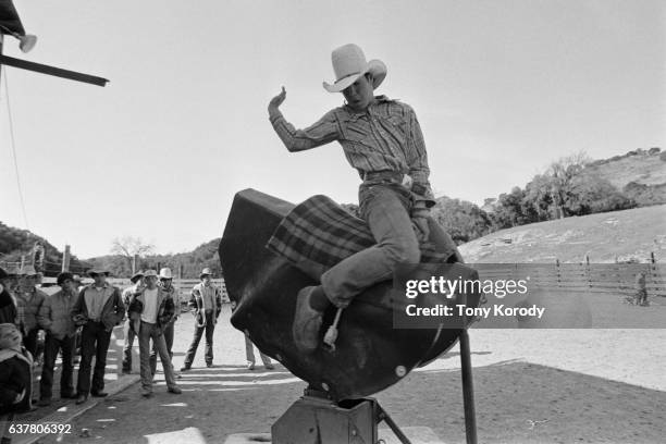 Young boy rides a mechanical bull at a rodeo.
