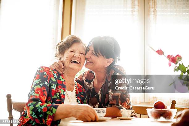 senior in relaxing mit ihrer tochter zu hause - mother and daughter kiss happy stock-fotos und bilder
