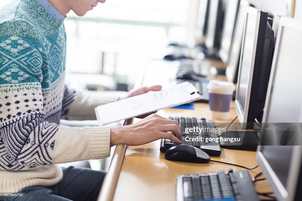 Young asian man with pc and clipboard
