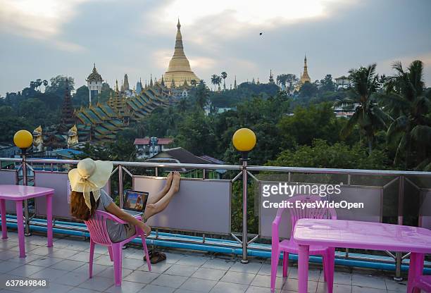 Tourist woman is watching the famous Shwedagon, or Shwedagon-Paya pagoda while working with a notebook and internet, making telephone calls or writes...