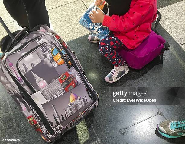 Child sitting on her luggage waits for departure beside a trolley showing the indian Taj Mahal building at Munich Airport on December 04, 2016 in...