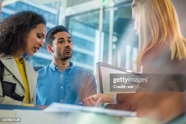 un couple parle à un caissier de banque - bank counters photos et images de collection