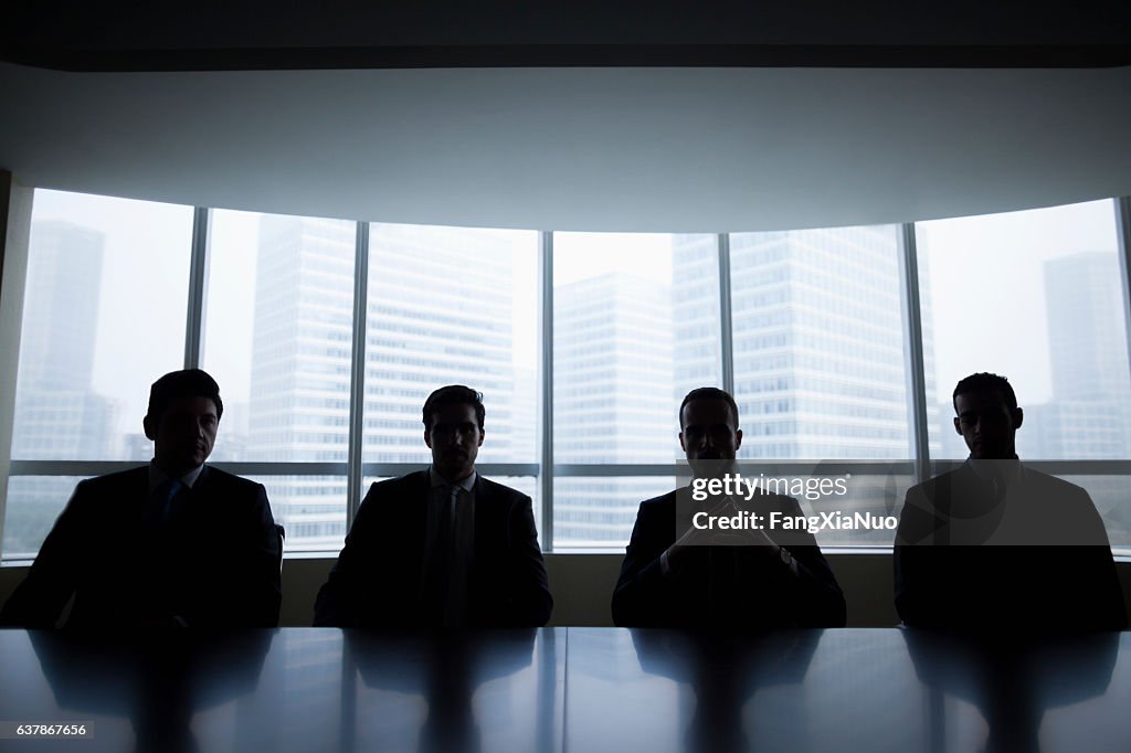 Fila de silueta de hombres de negocios sentados en la sala de reuniones