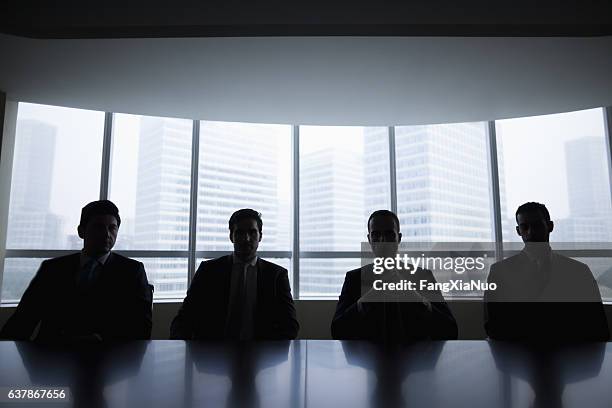 silhouette row of businessmen sitting in meeting room - group of people silhouette stock pictures, royalty-free photos & images