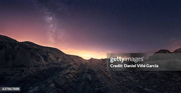 scenic view of desert and distant town at night - desert night stock-fotos und bilder