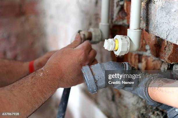 plumber working on pipes - tubazioni foto e immagini stock