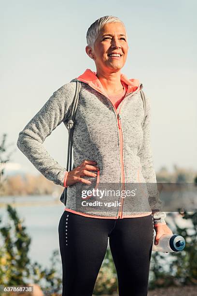 mature woman jogging in the city - woman hand on hip stock pictures, royalty-free photos & images