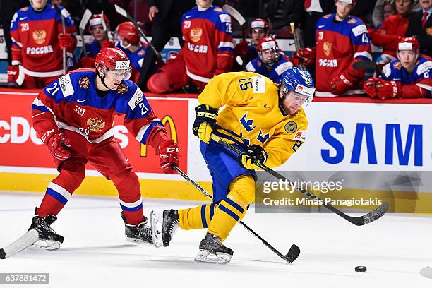 Sebastian Ohlsson of Team Sweden skates the puck against Denis Alexeyev of Team Russia during the 2017 IIHF World Junior Championship bronze medal...