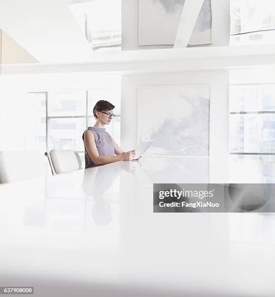 woman sitting using tablet computer in room - blank room stockfoto's en -beelden