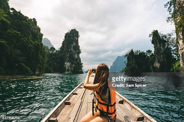 female tourist exploring lush jungle lake surrounded by limestone cliffs, khao sok national park, thailand - tailandia foto e immagini stock