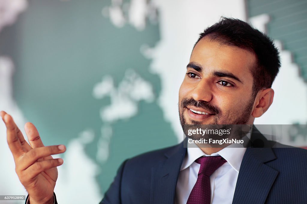 Empresário falando em sala com mapa na parede