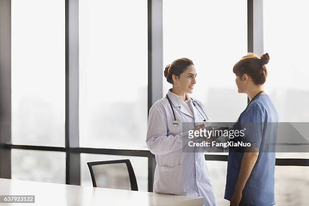 doctor and nurse talking together in office - district nurse stock pictures, royalty-free photos & images