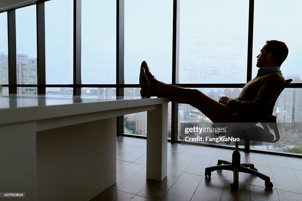 Man with feet propped up on table in meeting room