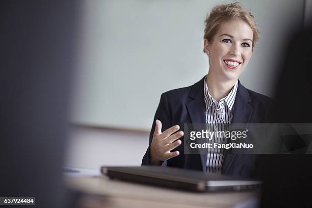 woman listening to colleagues in office meeting - masters degree imagens e fotografias de stock
