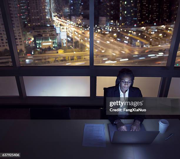 businesswoman working on laptop at night in office downtown - smart communicate elevation view stockfoto's en -beelden