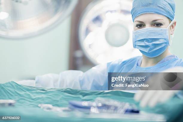 arzt greift nach chirurgischen werkzeugen im operationssaal des krankenhauses - paint tray stock-fotos und bilder