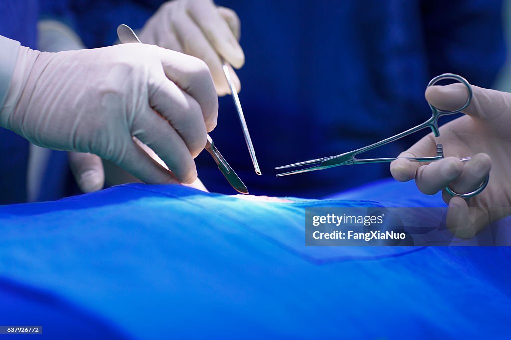 Mani dei medici che eseguono un intervento chirurgico in sala operatoria ospedaliera