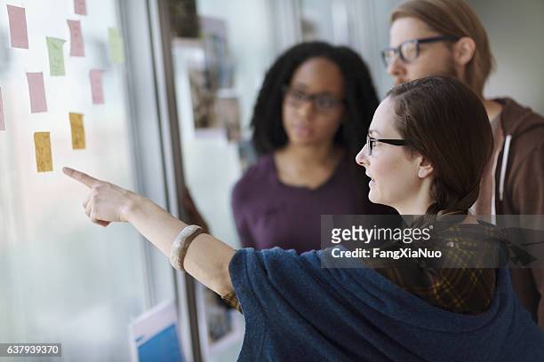 creative colleagues reviewing ideas on wall in studio office - kind stock pictures, royalty-free photos & images