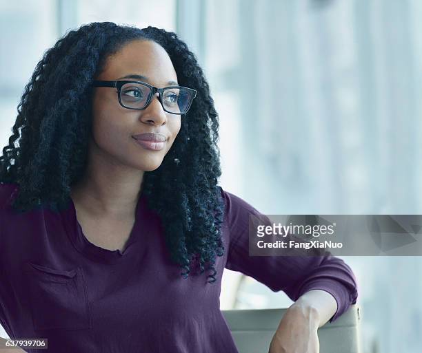 woman sitting confidently in office looking out of window - finding hope stock pictures, royalty-free photos & images