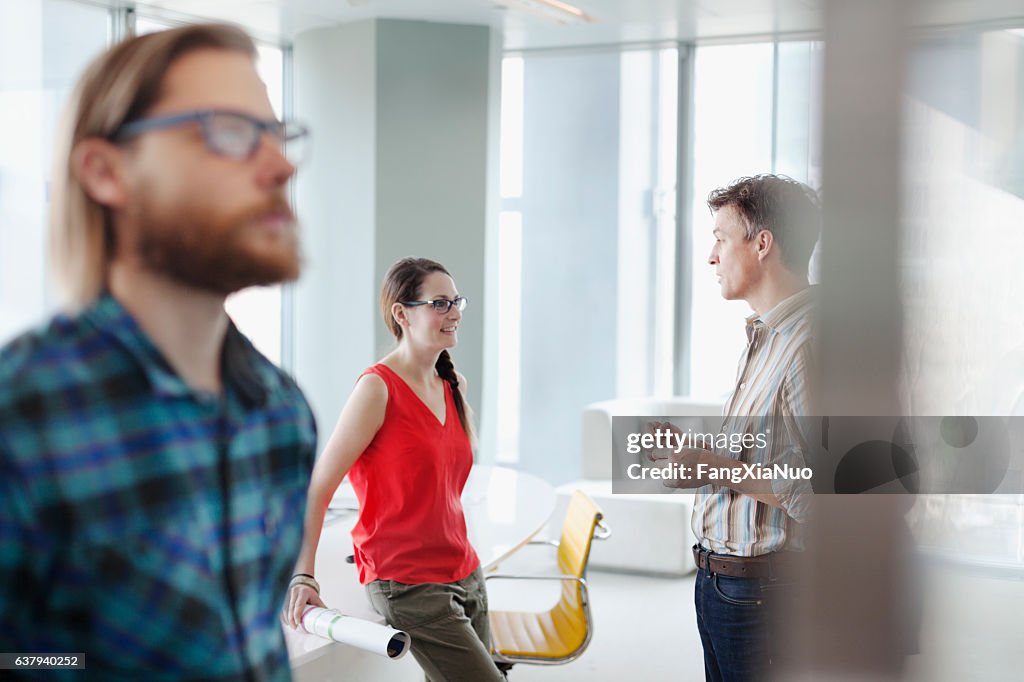 Colleagues talking together in bright office meeting room