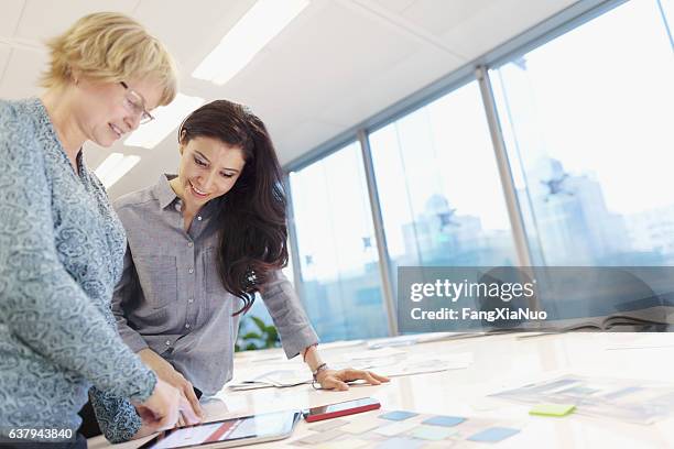 women reviewing plans on tablet computer in studio - patent stock pictures, royalty-free photos & images