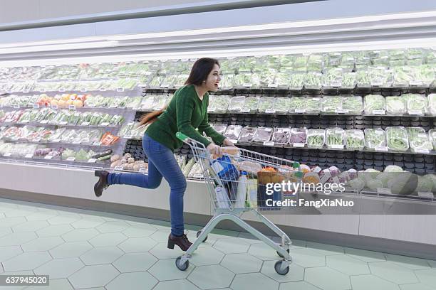 frau läuft mit einkaufswagen im supermarkt produzieren gang - sport shop stock-fotos und bilder