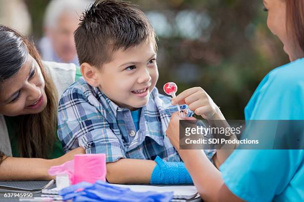 feliz niño herido recibe piruleta después de un examen médico - offering candy fotografías e imágenes de stock