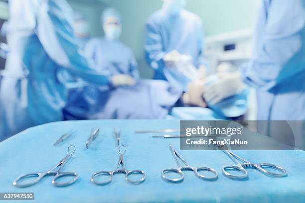 surgical tools arranged on tray with doctors in operating room - operating procedures standardization stock pictures, royalty-free photos & images