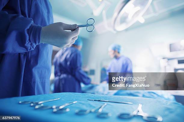 doctors performing surgery in hospital operating room - surgery stock pictures, royalty-free photos & images