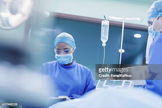 doctors performing surgery in hospital operating room - muster stock pictures, royalty-free photos & images