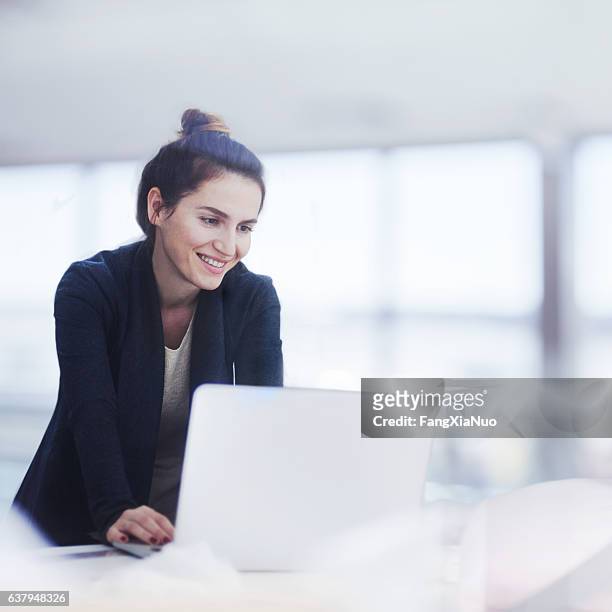 frau arbeitet auf laptop in hellen büro - euphoric female stock-fotos und bilder