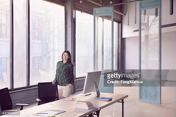 woman standing alone in large modern bright design office - art gallery owner stock pictures, royalty-free photos & images