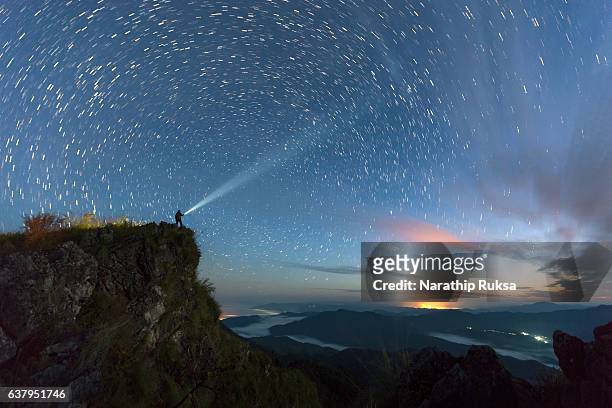 star trail over the mountain with the man light up the sky before sunsire, nan province, thailand - celebrities fotografías e imágenes de stock