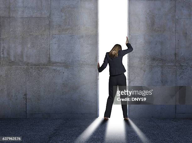 businesswoman pushing open concrete walls - closing door stock pictures, royalty-free photos & images