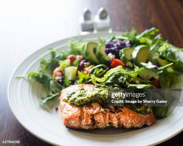 salmon fillet topped with arugula pesto and salad - mediterraanse gerechten stockfoto's en -beelden