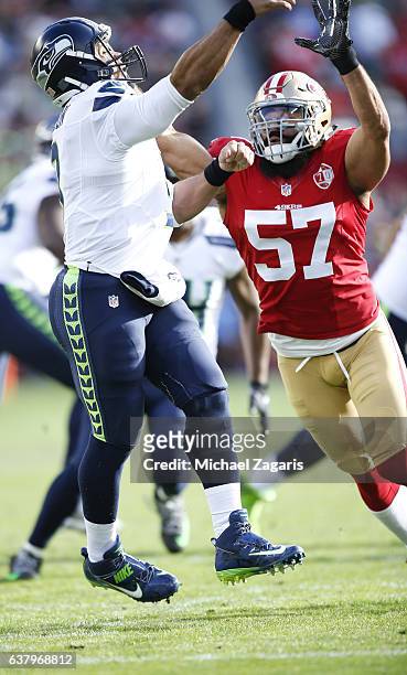 Russell Wilson of the Seattle Seahawks passes under pressure from Michael Wilhoite of the San Francisco 49ers during the game at Levi Stadium on...