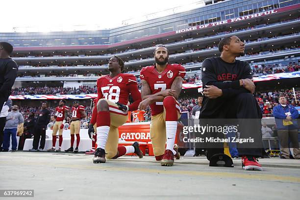 Eli Harold, Colin Kaepernick and Eric Reid of the San Francisco 49ers kneel on the sideline, during the anthem, prior to the game against the Seattle...