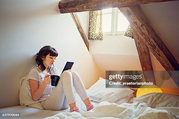 young teenage girl is reading ebook in her bed - girl in her bed stockfoto's en -beelden