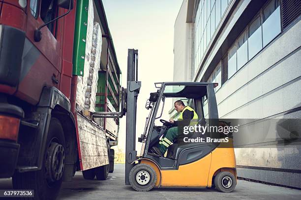 worker loading pallet with a forklift into a truck. - unloading stockfoto's en -beelden