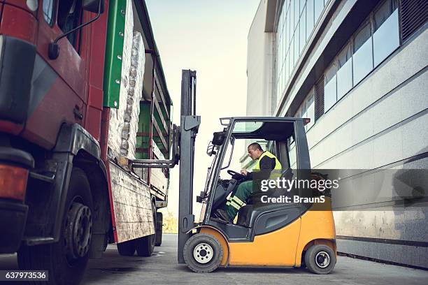 worker loading pallet with a forklift into a truck. - vorkheftruck stockfoto's en -beelden