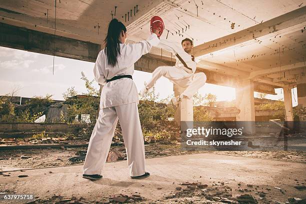 black belt martial artist practicing jump kick with sparring partner. - hög spark bildbanksfoton och bilder
