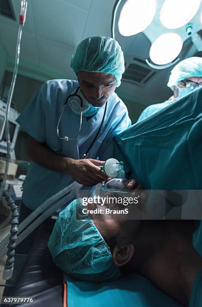 anesthesiologist putting oxygen mask to the patient on a surgery - verdovingsmiddel stockfoto's en -beelden