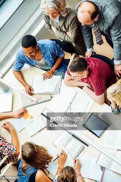 professors and students discussing at table in classroom - online guidance stock pictures, royalty-free photos & images