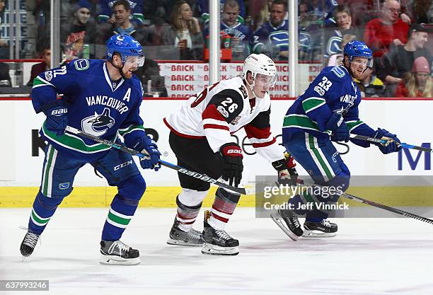 Michael Stone of the Arizona Coyotes and Daniel Sedin and Henrik Sedin of the Vancouver Canucks skate up ice during their NHL game at Rogers Arena...