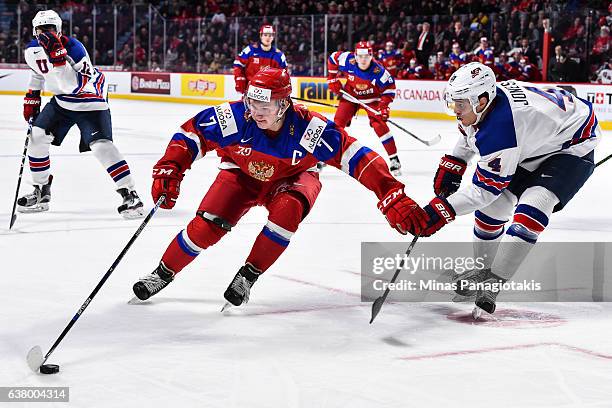 Kirill Kaprizov of Team Russia protects the puck from Caleb Jones of Team United States during the 2017 IIHF World Junior Championship semifinal game...