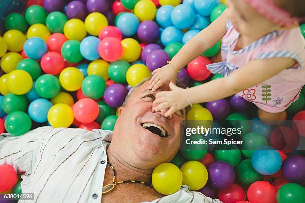 father playing with baby daughter with big smile - adult ball pit stock pictures, royalty-free photos & images