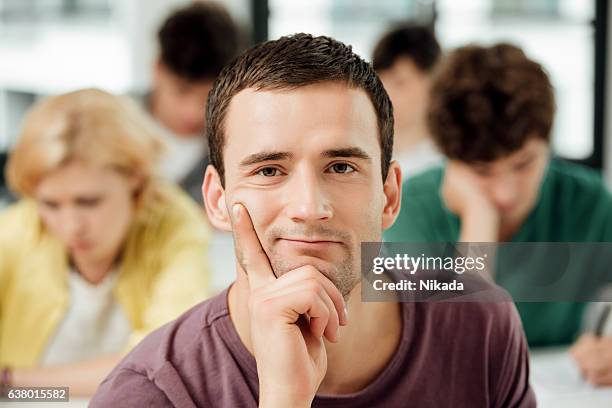 portrait of confident university student sitting with hand on chin - bored student stock pictures, royalty-free photos & images